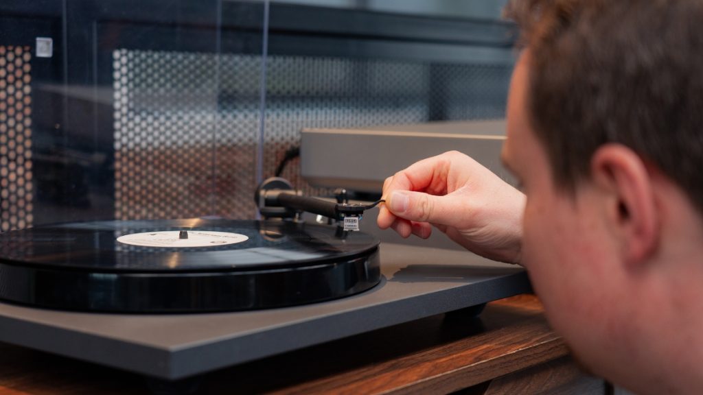 man adjusting turntable tonearm